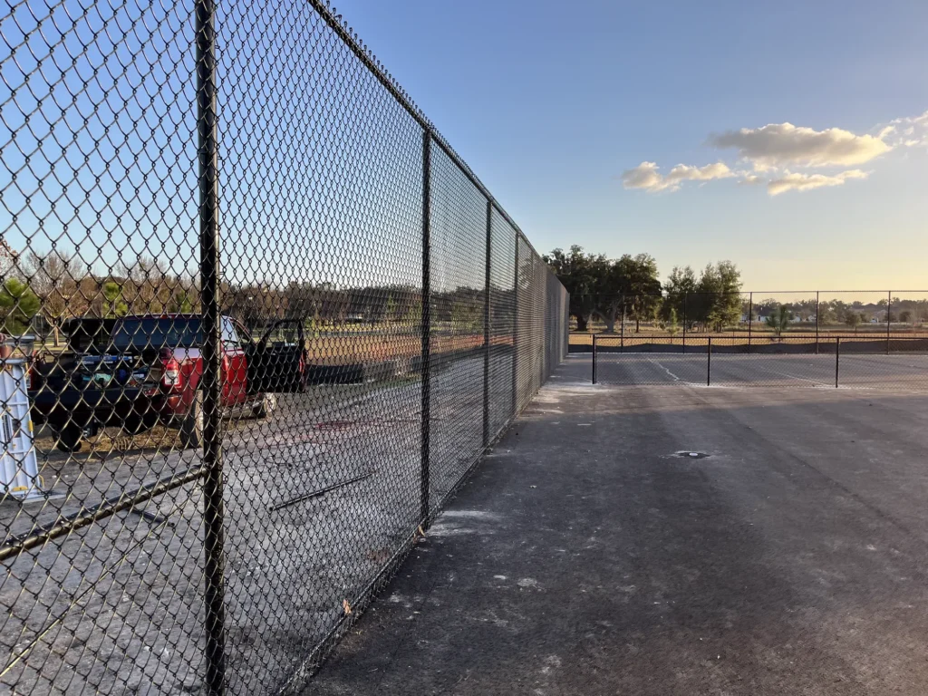 Black chain link fence enclosing a sports complex court in North Central Florida