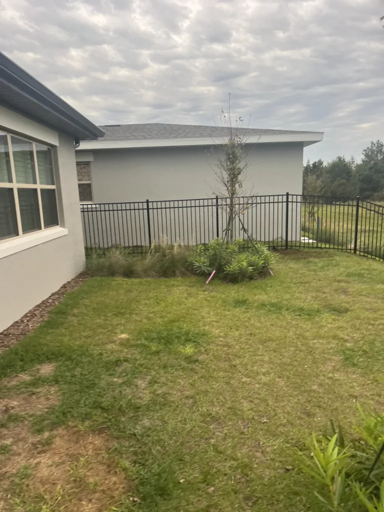 Black aluminum fence enclosing the rear yard of a new stucco home
