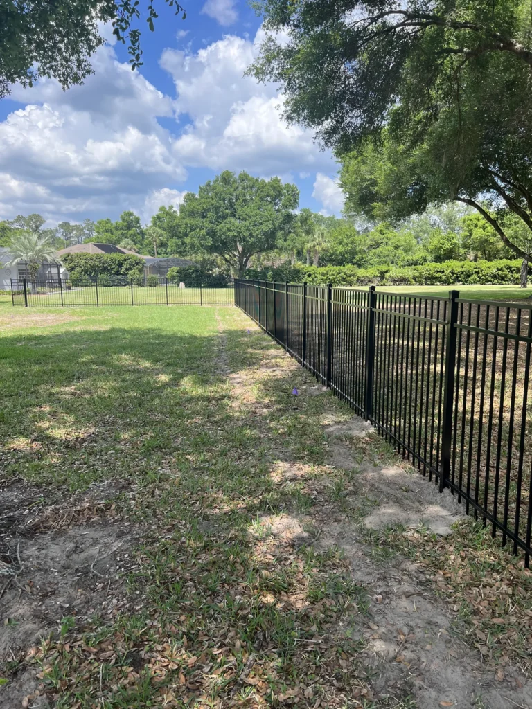 Black aluminum fence corner tying into an existing yard enclosure
