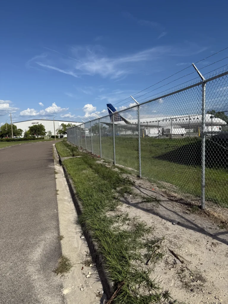 Airport perimeter security fence with barbed wire beside an aircraft hangar
