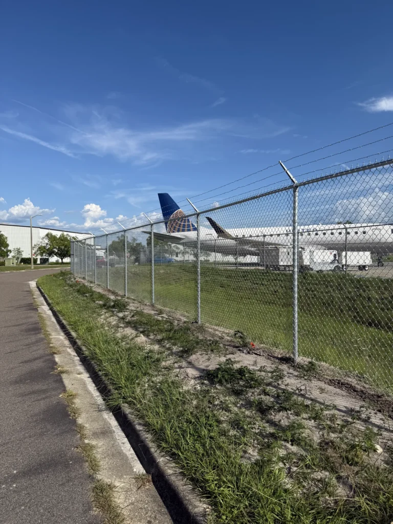 Chain link perimeter fence with barbed wire at an airfield
