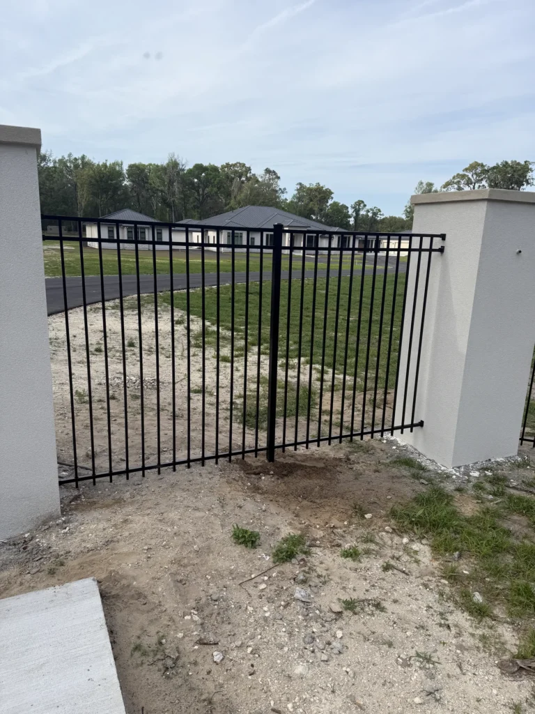 Black aluminum driveway gate at a ranch entrance