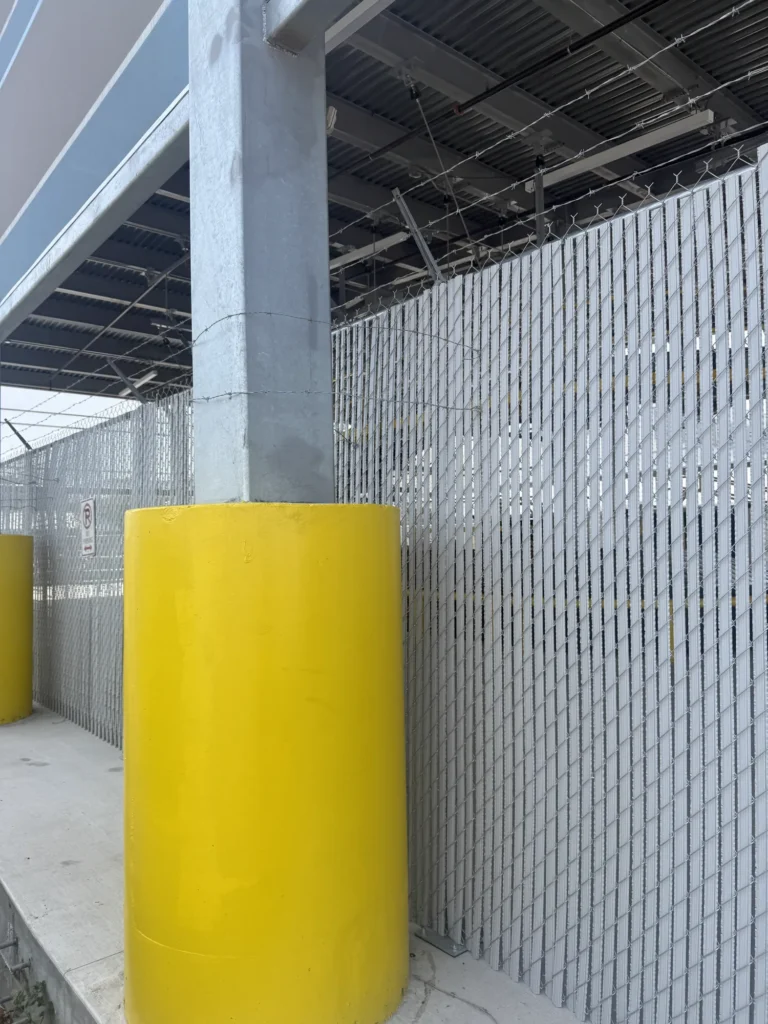 Gray privacy slat chain link fence beneath a loading canopy