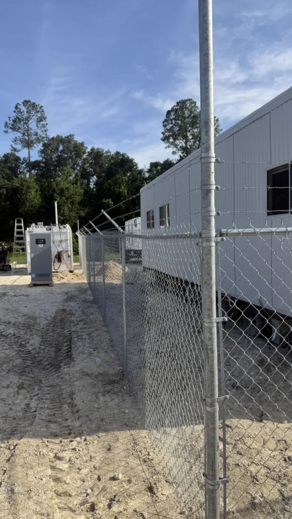 Galvanized chain link fence with barbed wire securing jobsite trailers
