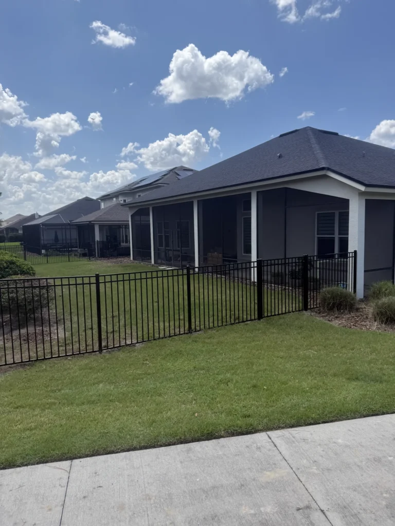 Black aluminum fence enclosing the backyard of a Florida home with a screened lanai